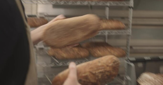 Busy Bearded male baker wearing apron in bakery packing bread for delivery