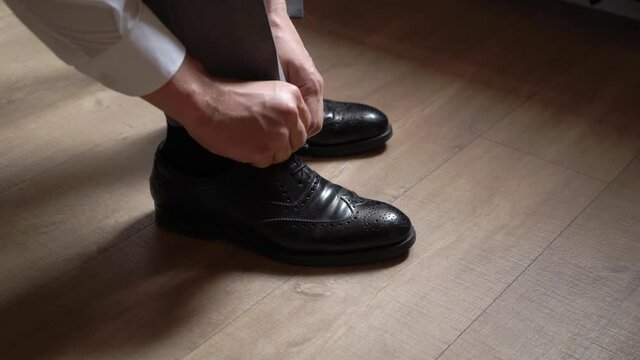 The young man put on the black shoes. Groom dresses for an event or wedding. High quality FullHD footage