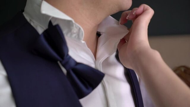 Bride fixing groom's bow tie in wedding day, lovely couple. High quality FullHD footage
