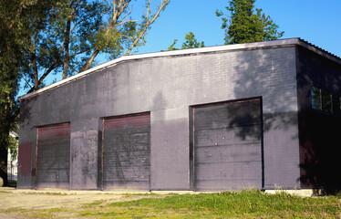 Fototapeta na wymiar Facade of a large dark hangar building with three closed doorways