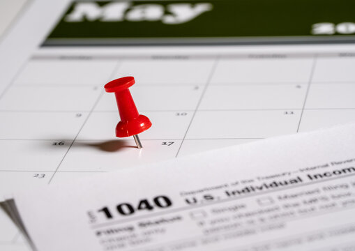 Calendar with pushpin inserted in the date for May 17 to illustrate the new tax return filing date of f17th May 2021.