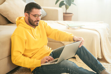 Man with glasses study online with laptop at home, doing video conference. Male looking at computer, remote work, distance learning and teaching concept.