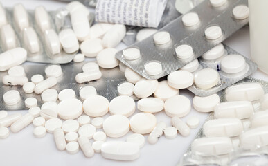 Fototapeta na wymiar Variety of medicine pills, tablets and capsules scattered on white surface