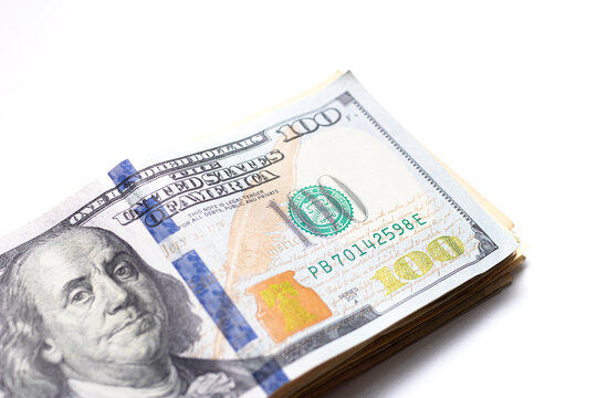 A Stack of American dollars isolated on white background. The new hundred-dollar bill is on top of the other banknotes. Close up photo and above view.
