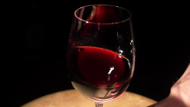 This slow motion video shows a glass of red wine being swirled around to release aromas.
