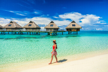 Beach vacation woman walking on Bora Bora beach in Tahiti, French Polynesia at luxury overwater bungalows hotels honeymoon destination. - obrazy, fototapety, plakaty
