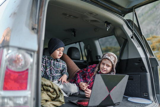 Two Boys Uses Laptop In Trunk Car