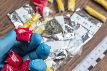 evidence of smuggling traffic: a package with an unknown drug in the hand of an expert against the background of other packages next to the forensic scale