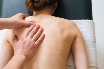 Top view of male masseur with strong hands professionally massaging scapulas and shoulders....