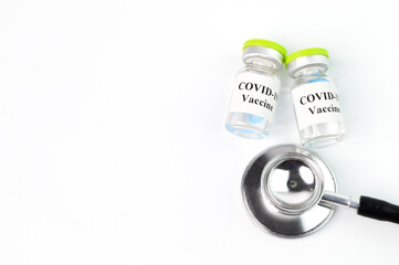 Covid-19 bottle vaccination and stethoscope over white background.