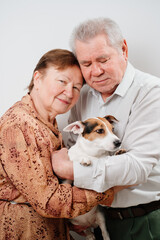 An elderly couple with a dog on a white background. 