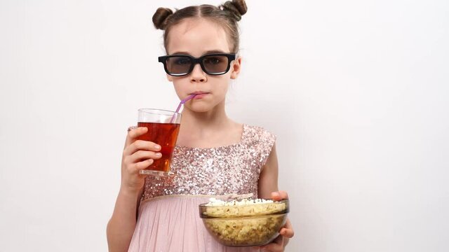 teen girl with glasses to watch 3D movies eats popcorn and drinks soda