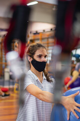 Fototapeta na wymiar young man with chinstrap mask in gym with ball