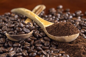 A close up photo of coffee beans and grounds on a table and on wooden spoons.