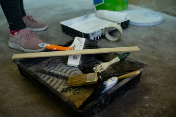 tools for painting a house or office, roller, brushes, white paint, wooden stirrer