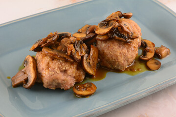 Two pork meatloaves with white wine mushroom sauce on serving plate