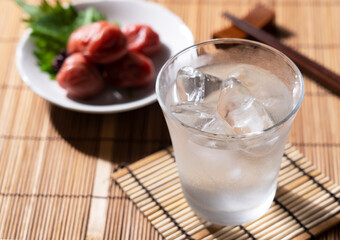 Shochu and pickled plums placed on a Japanese wooden background.