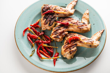 grilled chicken wings on a plate, restaurant serving, close-up top view