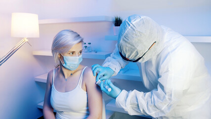 Young blond woman with medical mask receiving vaccine. Covid-19 immunization. High quality photo