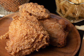 Fried chicken thighs and french fries in a basket with tomato sauce