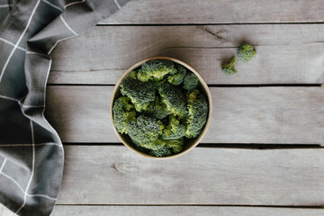 Green fresh broccoli in bowl on wooden background. Healthy eating concept