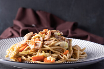 Yakisoba with pork in a ceramic plate on white background