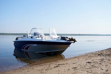 Naklejka premium A motorboat stands on the sandy bank of the river