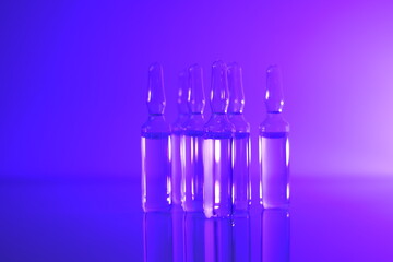 Medicine and Pharmacology concept. Vaccine ampoules. Glass  ampoules set in purple light.Biotechnology and Science.Ampoules with solution for injection.Health and beauty concept.vaccination