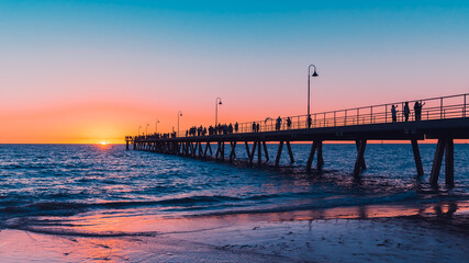Glenelg Beach beach foreshore view with people walking along the pier at sunset, South Australia
