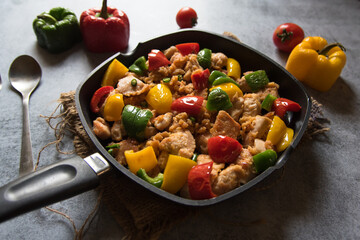 Close up of chicken and bell peppers stir fried in a pan on a background