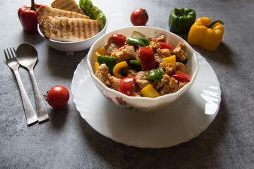 Close up of Chicken and bell peppers stir fried in a bowl with use of selective focus on a background