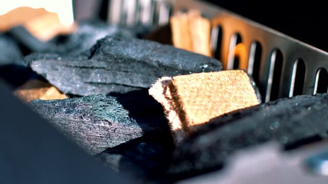 lighting a firestarter in a small grill filled with charcoal