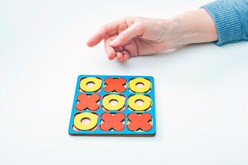 Hands elderly woman seniors play tic-tac-toe wood board game. Developmental game. Concept of family...