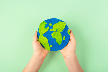 DIY and children creativity. Step by step instruction: make craft planet Earth from CD and plasticine. Step 4 kids hands hold finished craft. World Earth or Oceans Day.