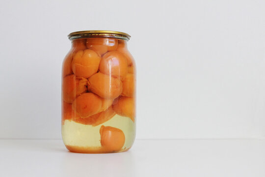 Canned Apricots In A Glass Jar On A White Table