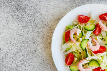 fresh summer salad of peking cabbage, cherry tomato, cucumber and shrimps with copy space text