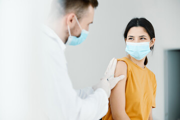 a doctor and a dressing gown seals the injection on the shoulder of a woman covid vaccination