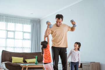 happy father and kid doing exercise together. portrait of healthy family workout at home. kid disturb his daddy while doing sport