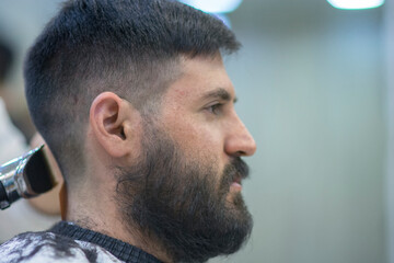 Obraz premium Portrait of a Bearded Caucasian Man with black hair, having a haircut 