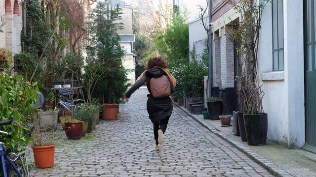 Caucasian young woman running away in a small street in Paris, France