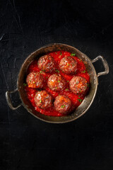 Meatballs in a skillet, shot from the top on a black background
