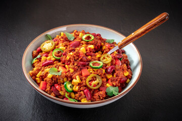 Chili con carne with a spoon on a black background