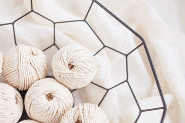 Handmade macrame braiding and cotton threads in basket on white background. Light  image good for macrame and handicrafts banners and advertisement. Copy space. Top view