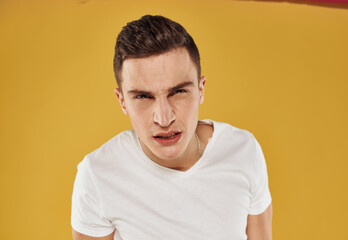 Obraz premium Man in a white T-shirt on a yellow background portrait close-up model cropped view gesturing with hands