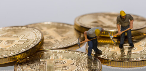 two miner working on golden bitcoins crypto currency with gray panorama