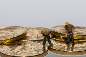 Fototapeta na wymiar two miner working on golden bitcoins crypto currency with gray