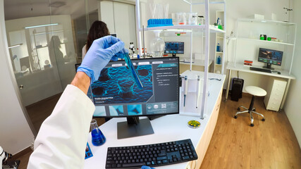 FPV of biologist doctor checking DNA image typing on pc, while colleague bringing tubes with samples, Scientists examining vaccine evolution in medical lab using high tech for scientific research.