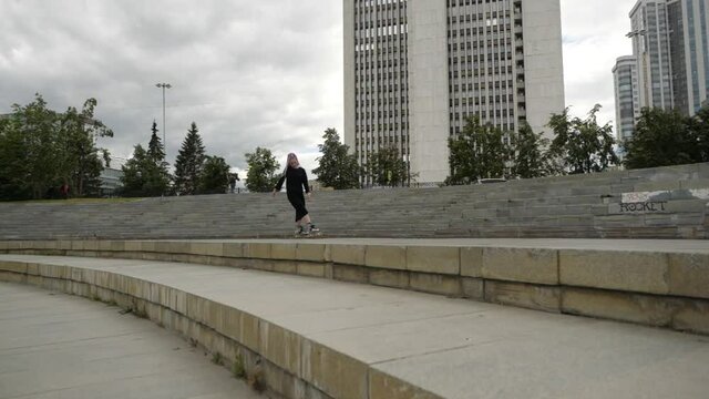 video of an interesting girl with a bright appearance who skates around the city on roller skates in cloudy weather. High quality FullHD footage