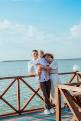 Fototapeta na wymiar A young family with a little daughter, a toddler, in light clothes in the summer on the seashore, enjoy their vacation. Happy family and children. Summer vacation and tourism