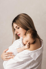 A loving mother carries her newborn baby at home. portrait of a happy mother holding a sleeping...